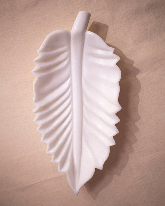 Close-up of organic leaf contour and smooth finish on white marble Urli