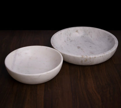 White marble dual-purpose Urli fruit bowl styled on a dining room table