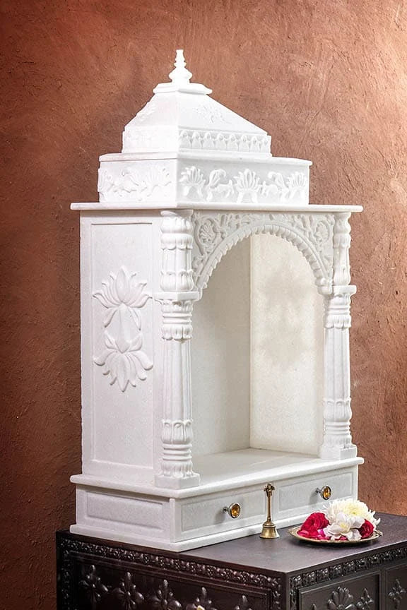Close-up of carved toran archway and pillars on marble pooja mandir