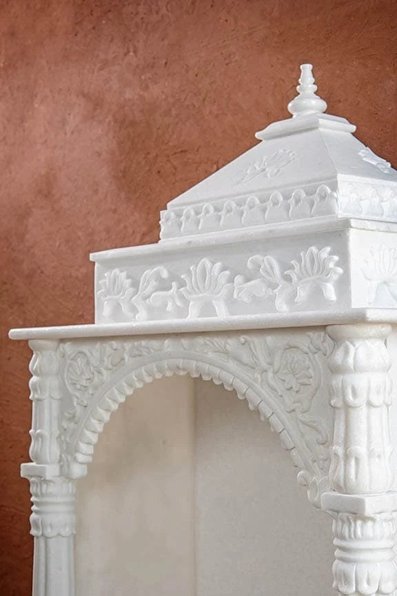 Close-up of carved toran archway and pillars on marble pooja mandir
