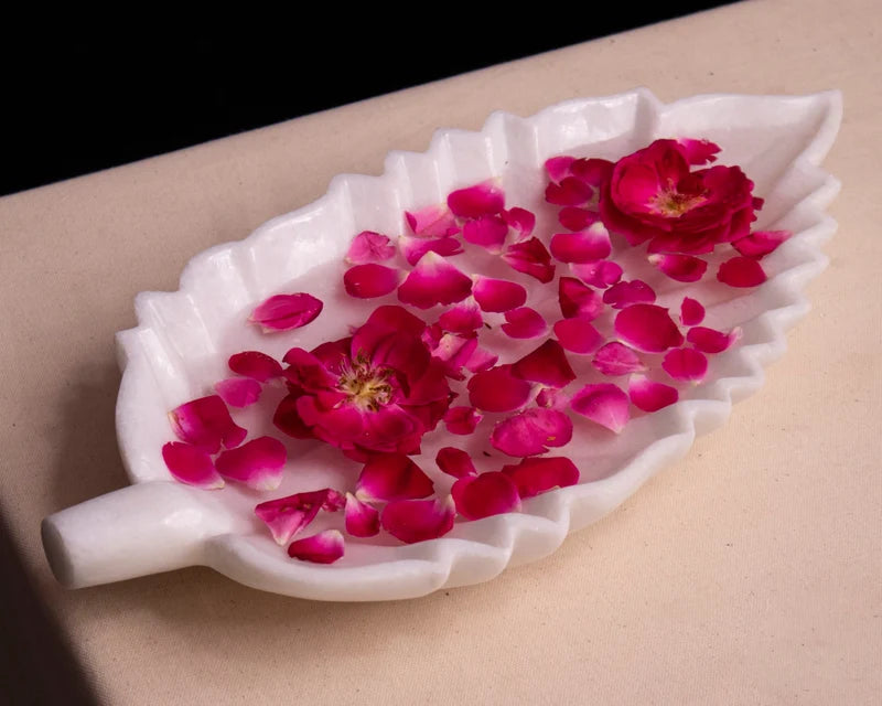 Leaf-shaped white marble Urli bowl decorated with floating flowers and candles for home decor