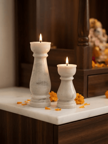 Elegant white marble pillar diya set beautifully lit on a festive home mandir altar