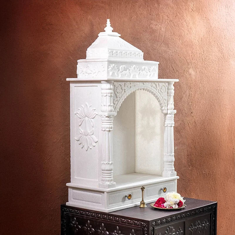 Close-up of carved toran archway and pillars on marble pooja mandir