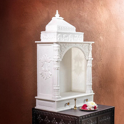 Close-up of carved toran archway and pillars on marble pooja mandir