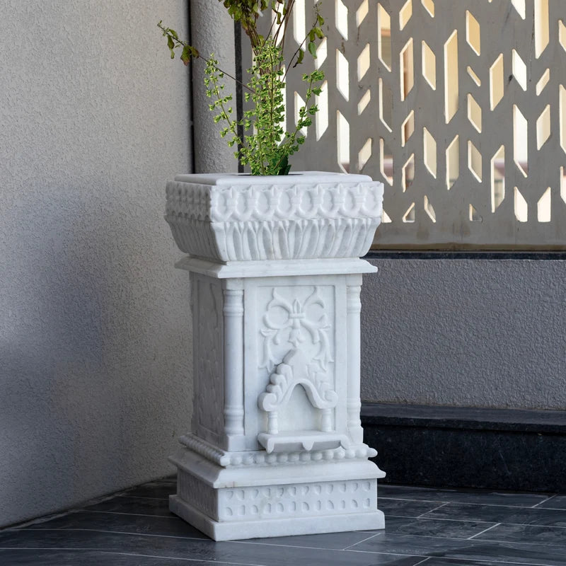 Close-up of intricate traditional stone carvings on white marble Tulsi planter