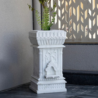 Close-up of intricate traditional stone carvings on white marble Tulsi planter