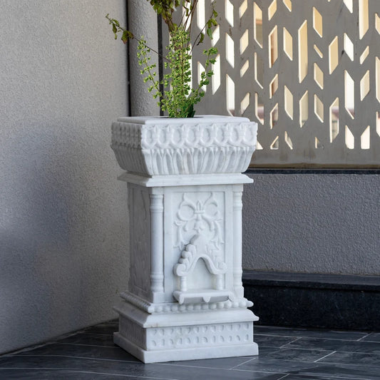 Close-up of intricate traditional stone carvings on white marble Tulsi planter
