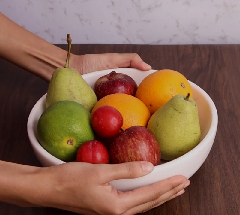 White marble dual-purpose Urli fruit bowl styled on a dining room table