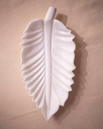 Close-up of organic leaf contour and smooth finish on white marble Urli